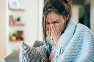 Women blowing her nose wrapped in a blanket on sick leave