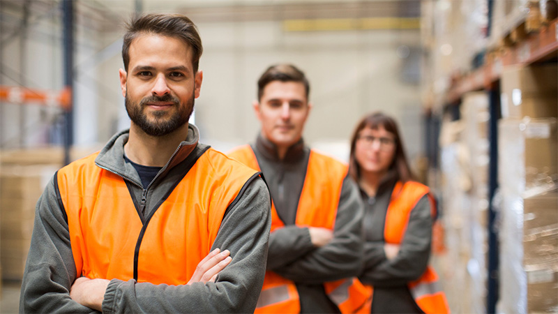 Three warehouse employees stood with arms folded