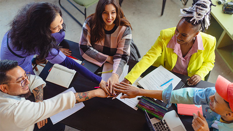 Happy employees putting their hands together