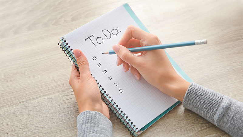 Person writing down tasks on a to do list